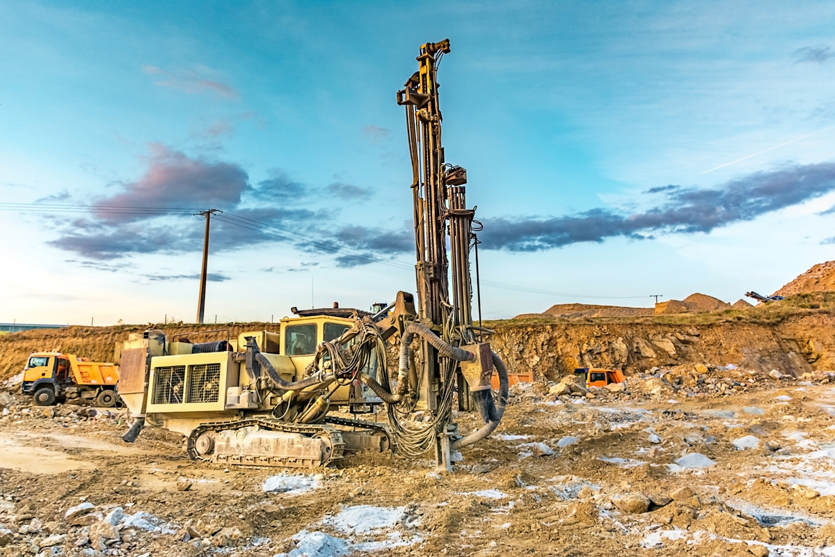 A yellow hole drilling machine drilling into the soil of an El Paso construction site.