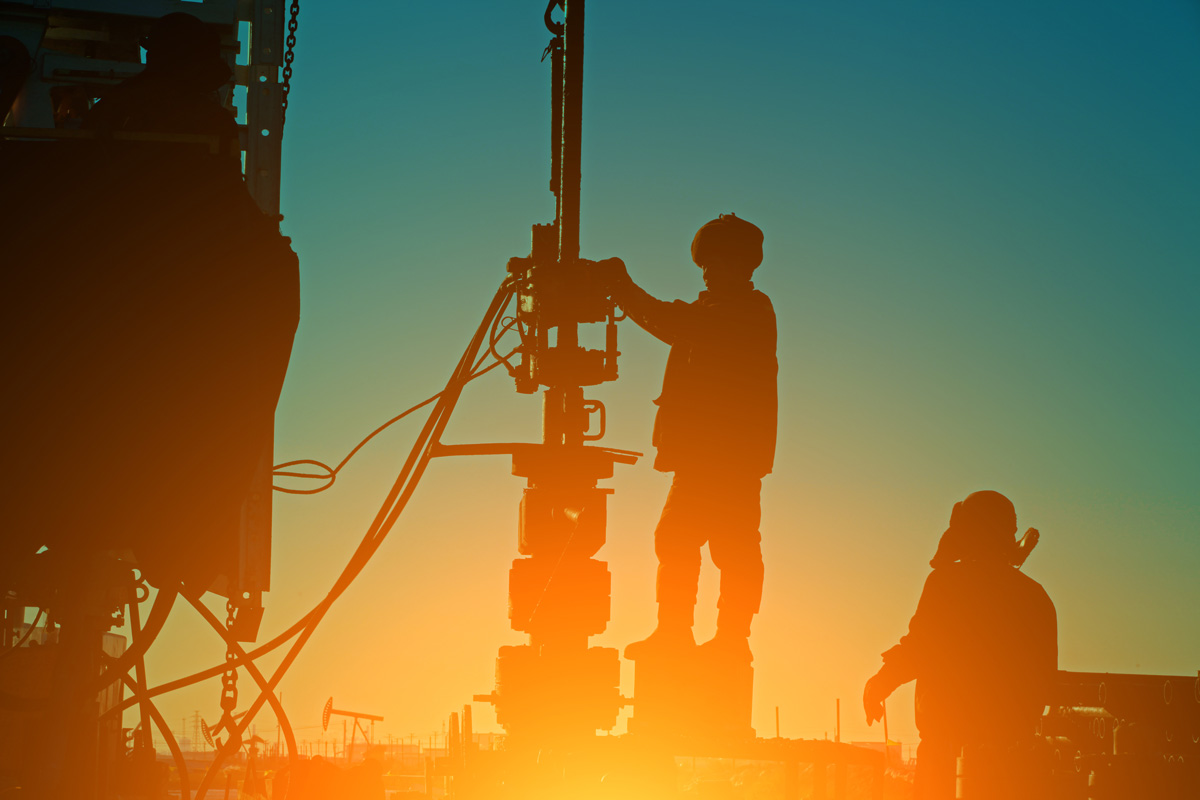 The silhouettes of two people pier drilling at a construction site in El Paso.